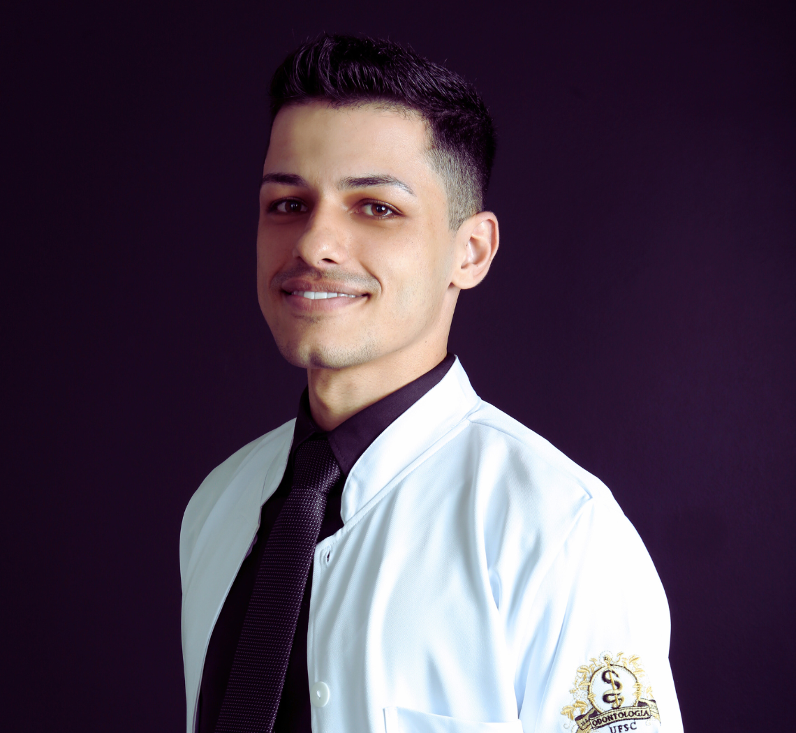 Dentista 24 horas de plantão pronto para atendimento de urgência e emergência, sorridente usa jaleco branco e gravata preta, transmitindo profissionalismo e confiança no atendimento odontológico do sistema dentista 24 horas e agendamento de pacientes.