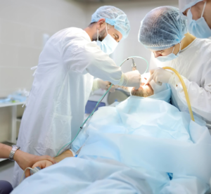Equipe de dentistas realizando uma cirurgia odontológica em um paciente sob anestesia, em um ambiente hospitalar esterilizado. Ilustrando o que é oferecido no sistema dentista 24 horas.